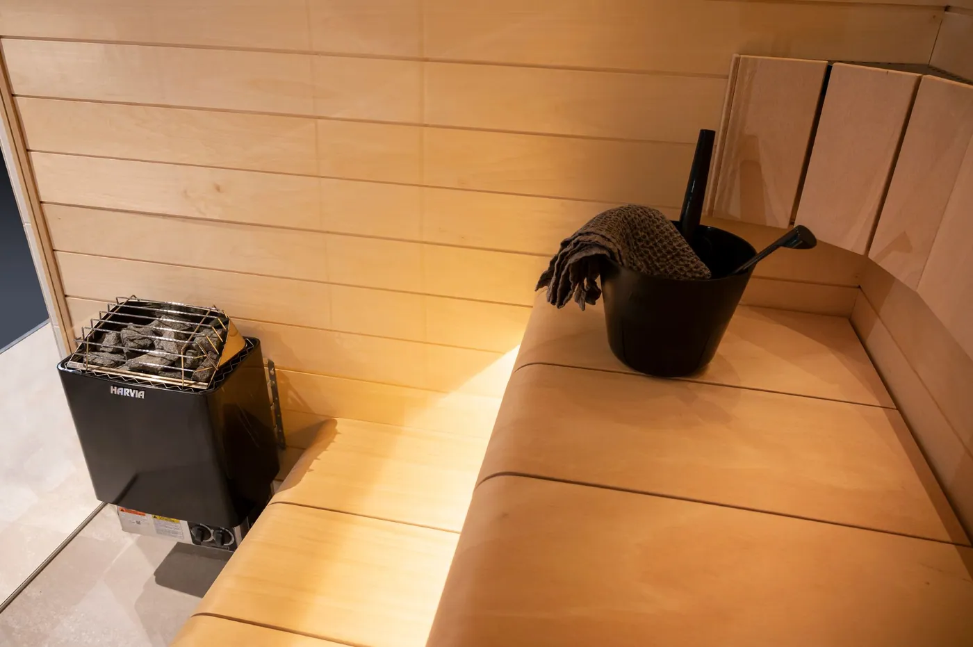 Harvia KIP Electric Sauna Heater, 6 kW · Built-in controls · Black — installed in a sauna